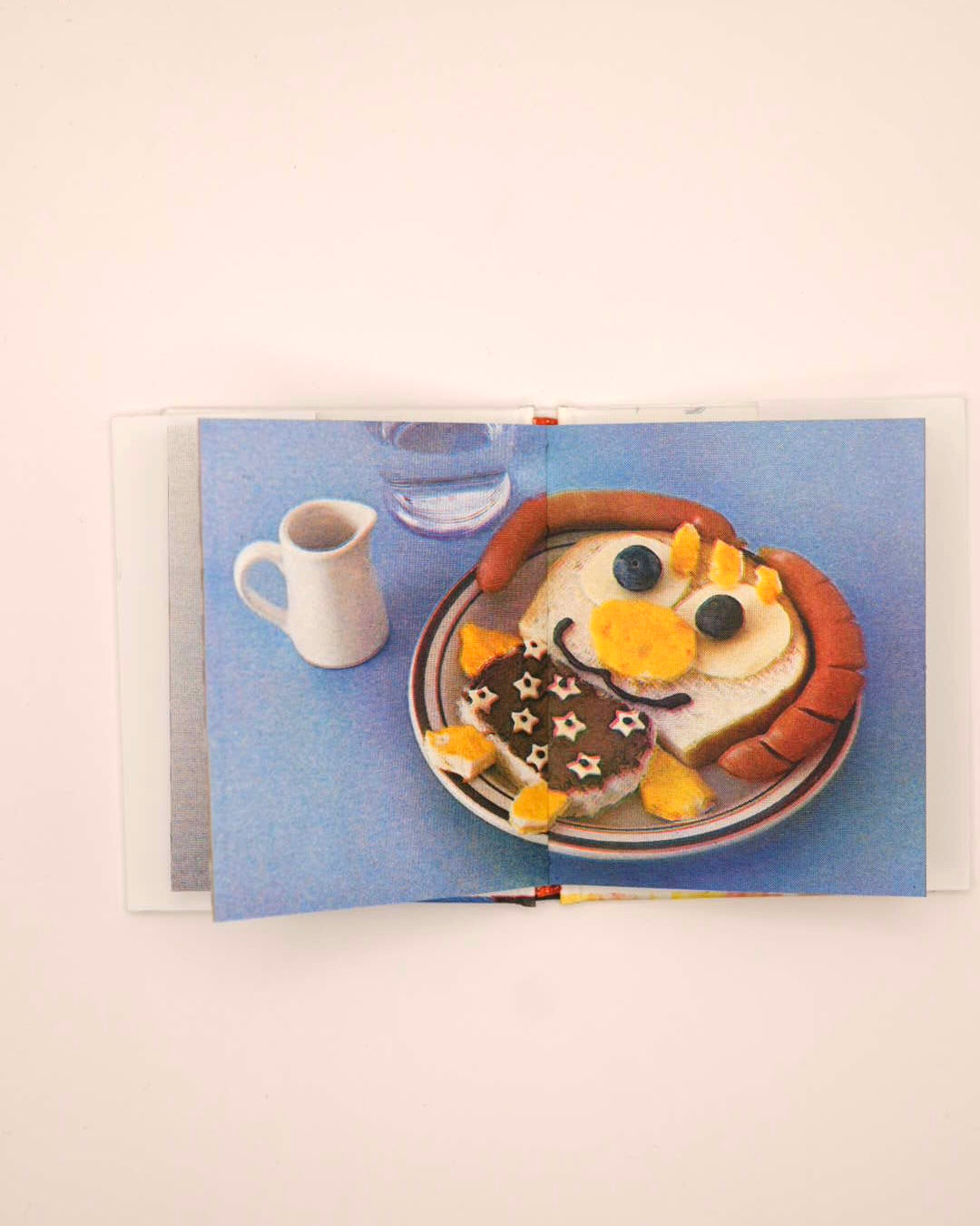 A square art print featuring a whimsical illustration of a cartoon character in a chef hat mixing batter, with the text 'Cooking with Happy' above, shown against a light gray background.